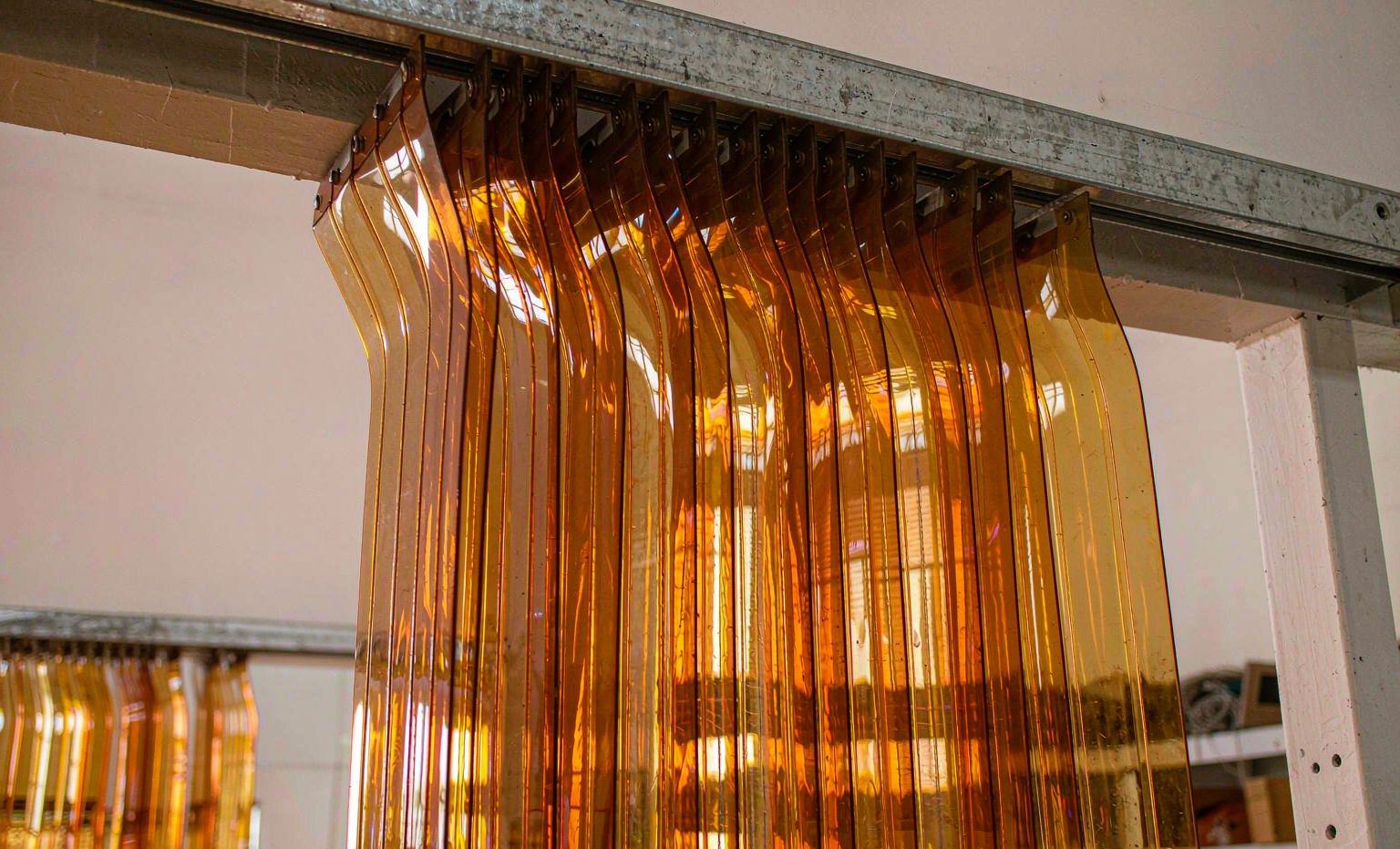 Amber-tinted PVC strip curtains hanging in a warehouse doorway